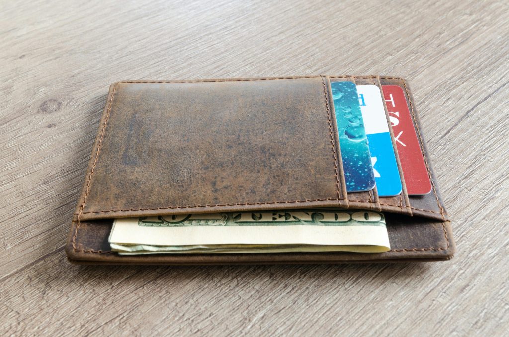 pexels-photo-915915-915915 A brown leather wallet with cash and credit cards on a wooden surface.